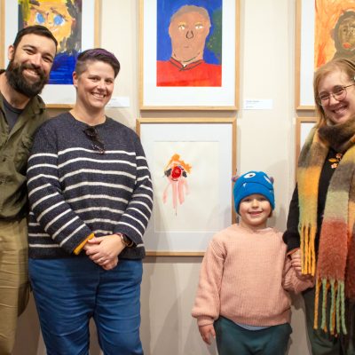 Family looking at their daughter’s self portrait at the opening of Heart and Soul of the Country.